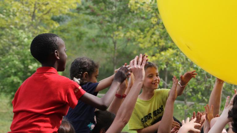 nens i nenes agafant un globos groc molt gran